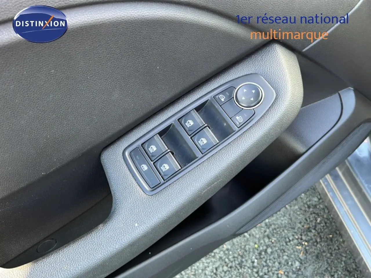 Gros plan sur la commande des vitres électriques côté conducteur d'une Renault Clio gris schiste métal, intérieur noir.