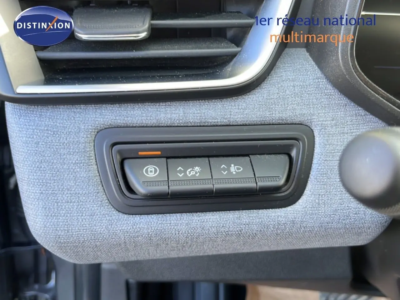 Détail intérieur montrant les commandes d’éclairage et de verrouillage sur tissu gris dans une Renault Clio 2025.