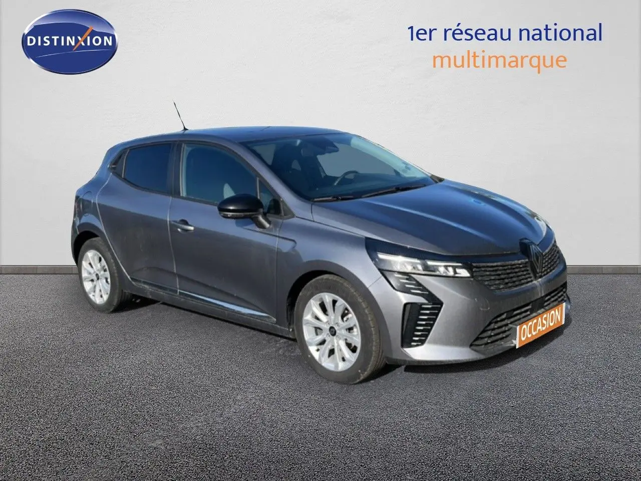 Renault Clio 2025 gris schiste métal en 3/4 avant droit, avec calandre distinctive et feux LED modernes.