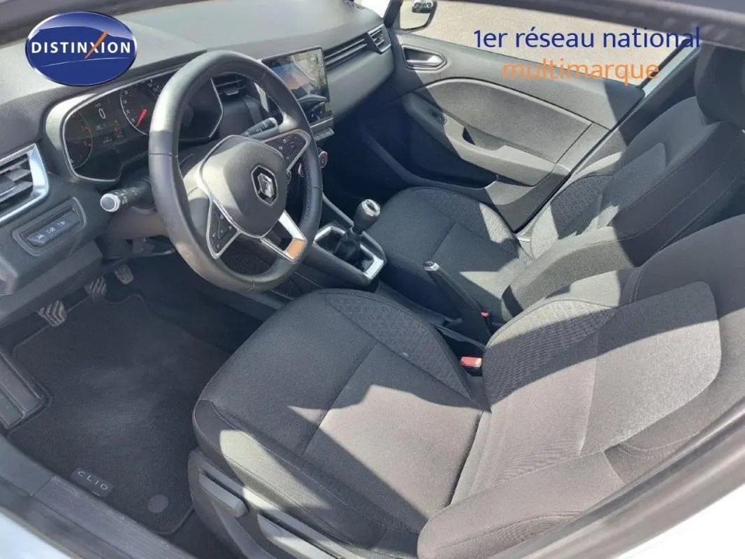 Vue intérieure côté conducteur de la Renault Clio blanche 2020, avec volant multifonction et boîte manuelle visible.