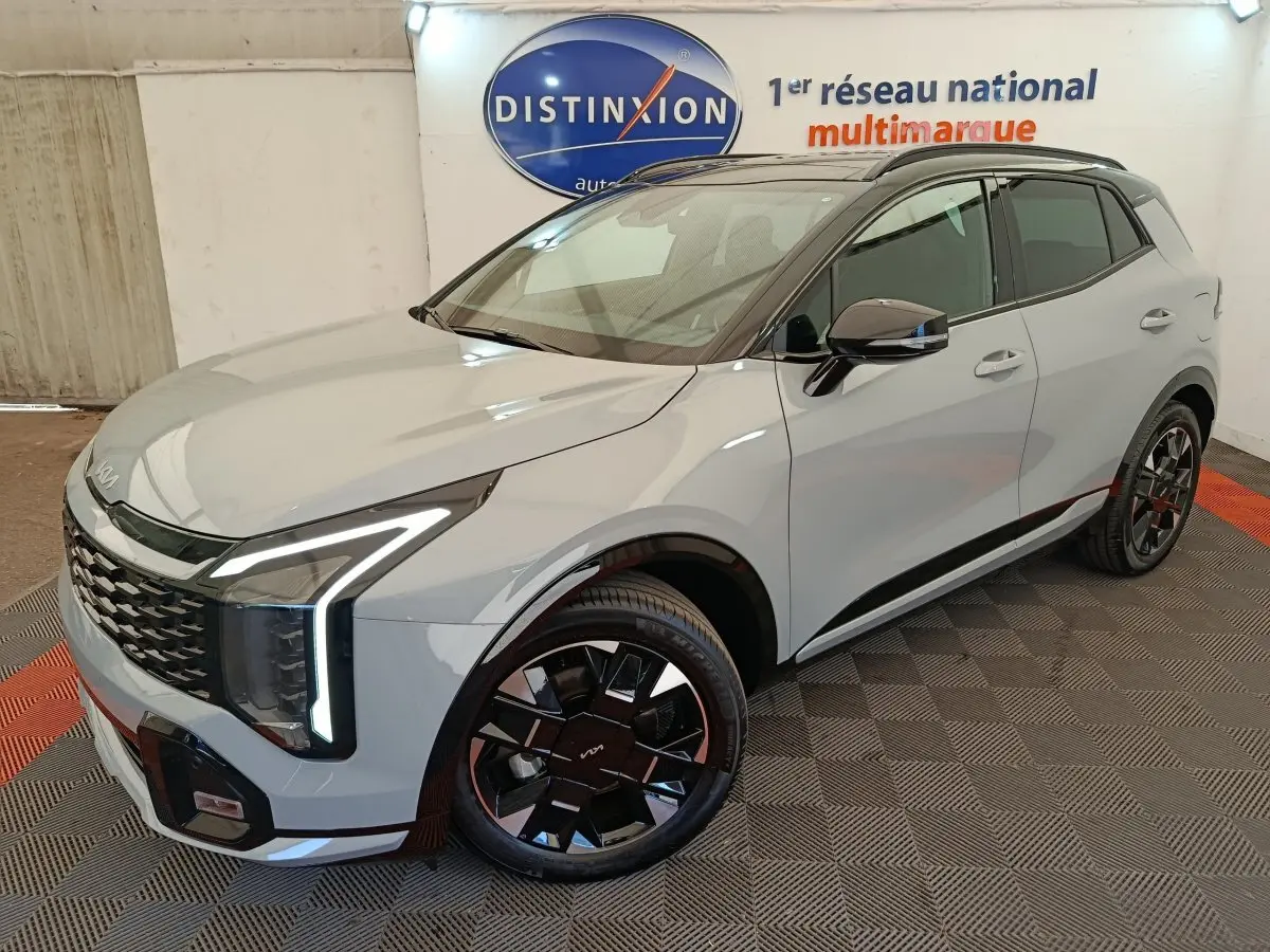KIA Sportage gris clair en 3/4 avant droit, avec feux LED verticaux distinctifs et jantes noires stylées.