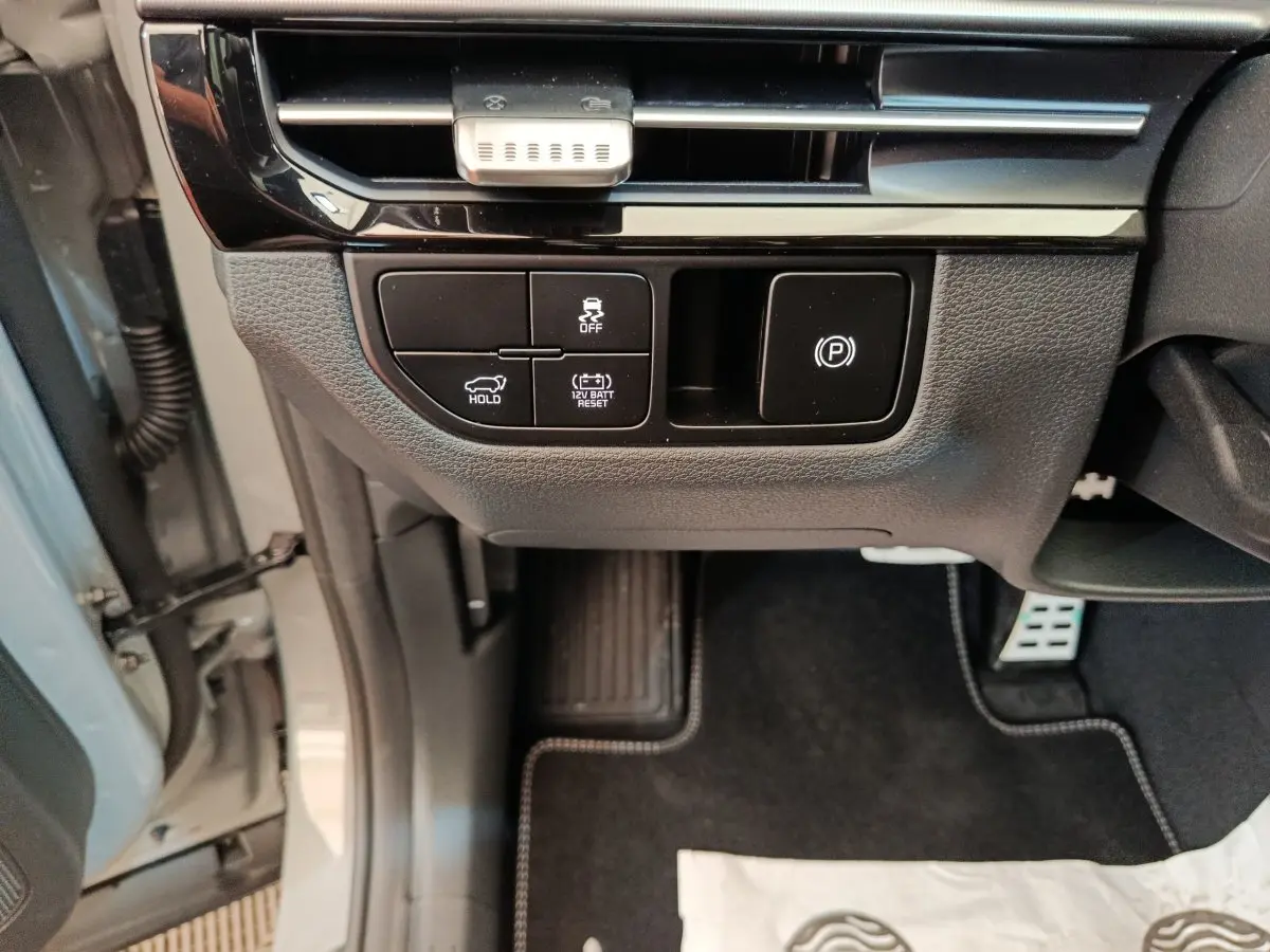Vue intérieure côté conducteur du tableau de bord et commandes basses d’un KIA Sportage gris clair 2026.