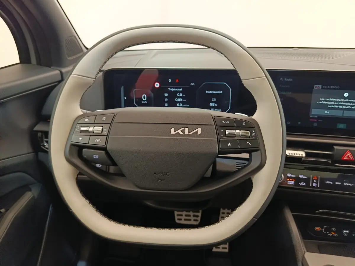 Vue intérieure centrée sur le volant bicolore gris clair et noir du Kia Sportage 2026 avec tableau de bord numérique.