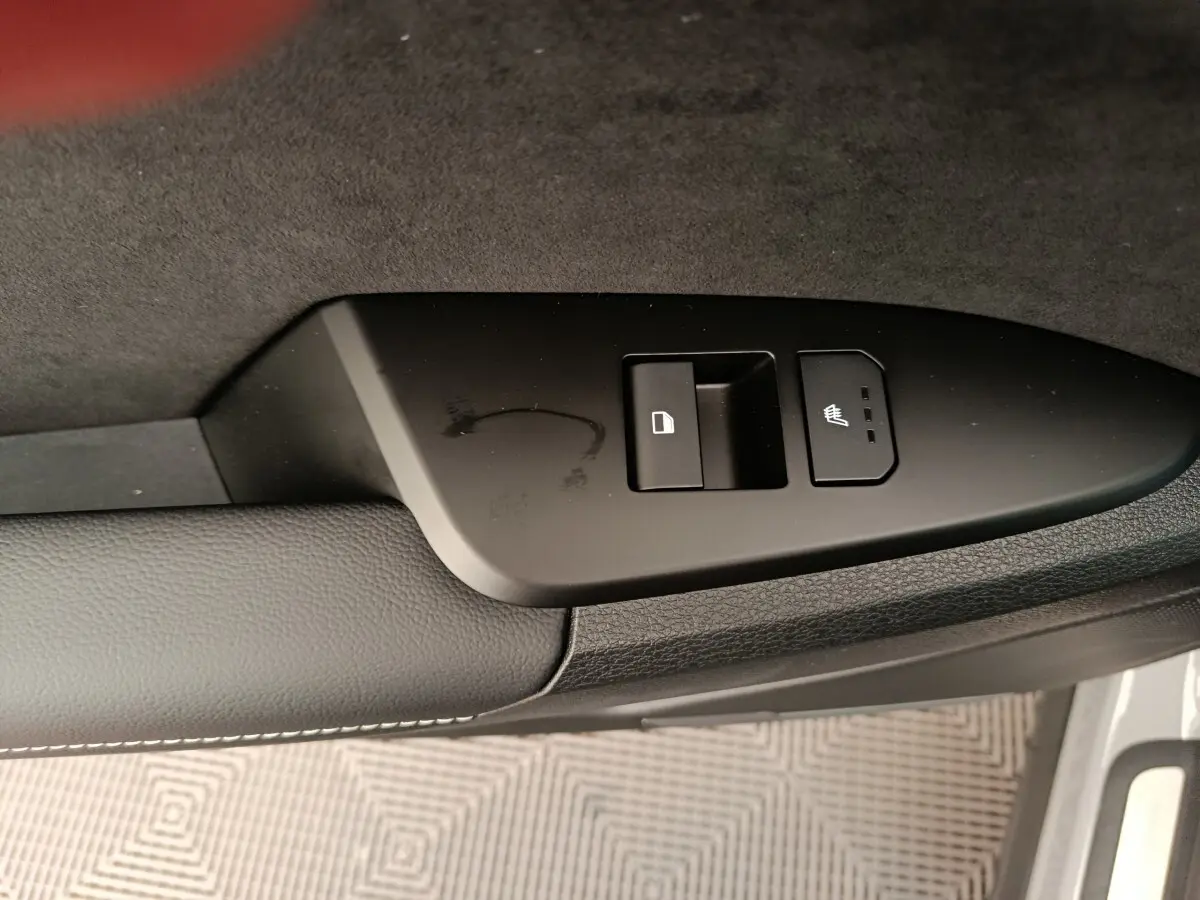 Détail de la commande de verrouillage et de siège chauffant sur la portière côté conducteur du KIA Sportage gris clair.