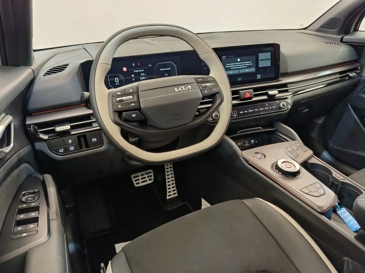 Intérieur avant du Kia Sportage 2026, vue du poste de conduite avec volant bicolore et écran tactile central.