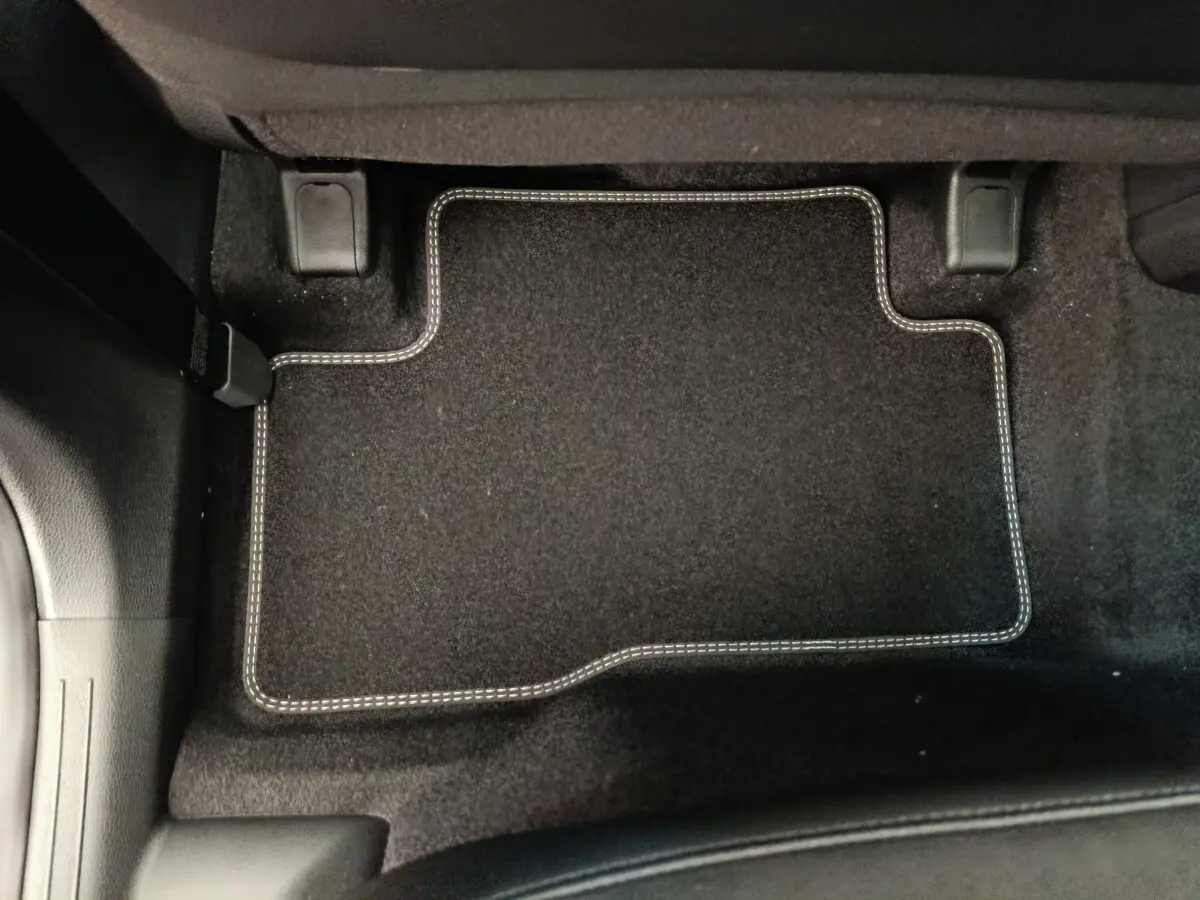 Tapis de sol noir avec surpiqûres blanches côté passager arrière du Kia Sportage gris clair 2026.