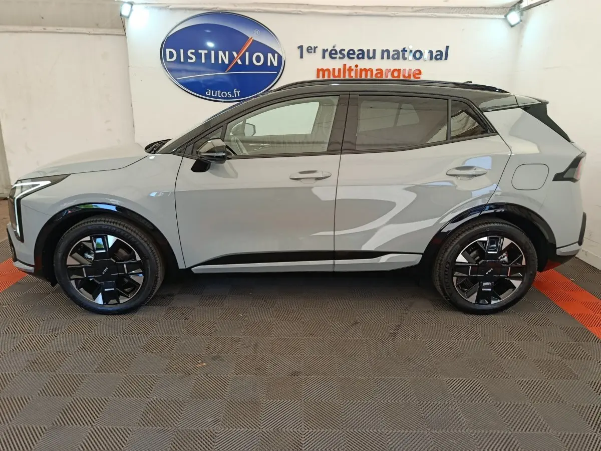 Vue de profil côté gauche du KIA SPORTAGE gris clair avec jantes noires et toit noir contrasté.