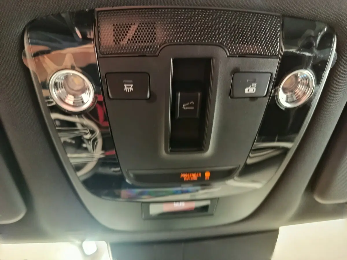 Vue en gros plan du plafonnier intérieur noir brillant du KIA SPORTAGE 2026 avec commandes d’éclairage et alerte passager.