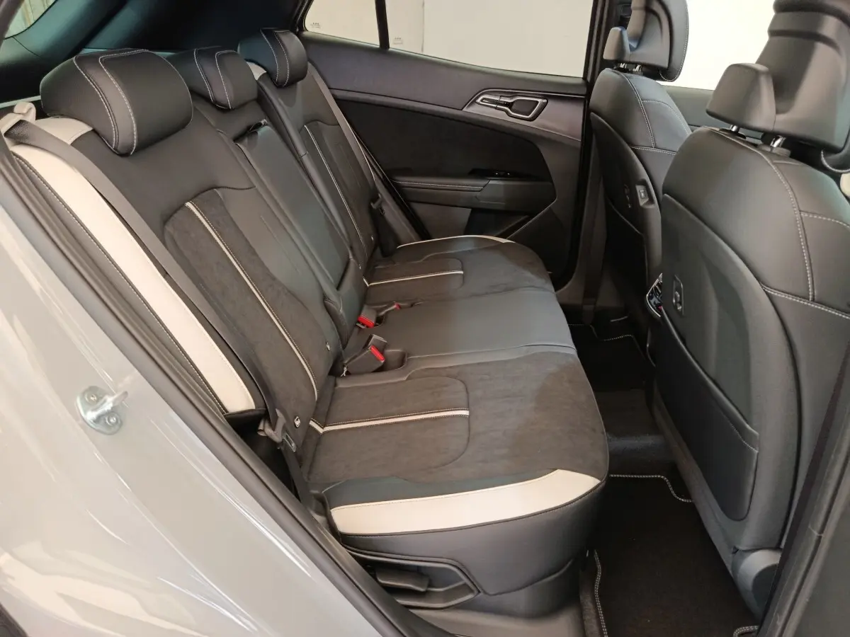 Vue intérieure côté gauche des sièges arrière gris foncé et noir avec surpiqûres blanches du Kia Sportage 2026 gris clair.