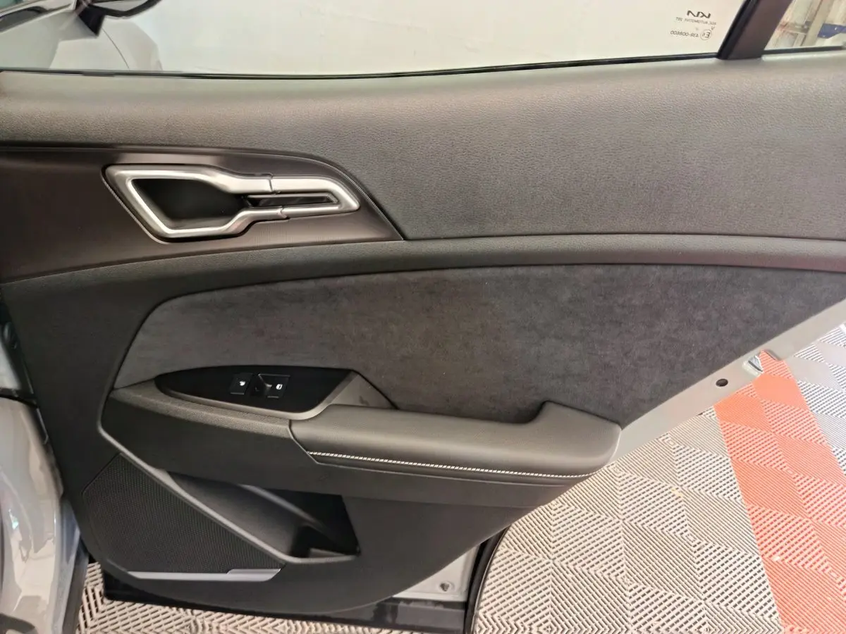 Gros plan sur la porte intérieure côté gauche du Kia Sportage 2026, avec garniture noire et poignée argentée.