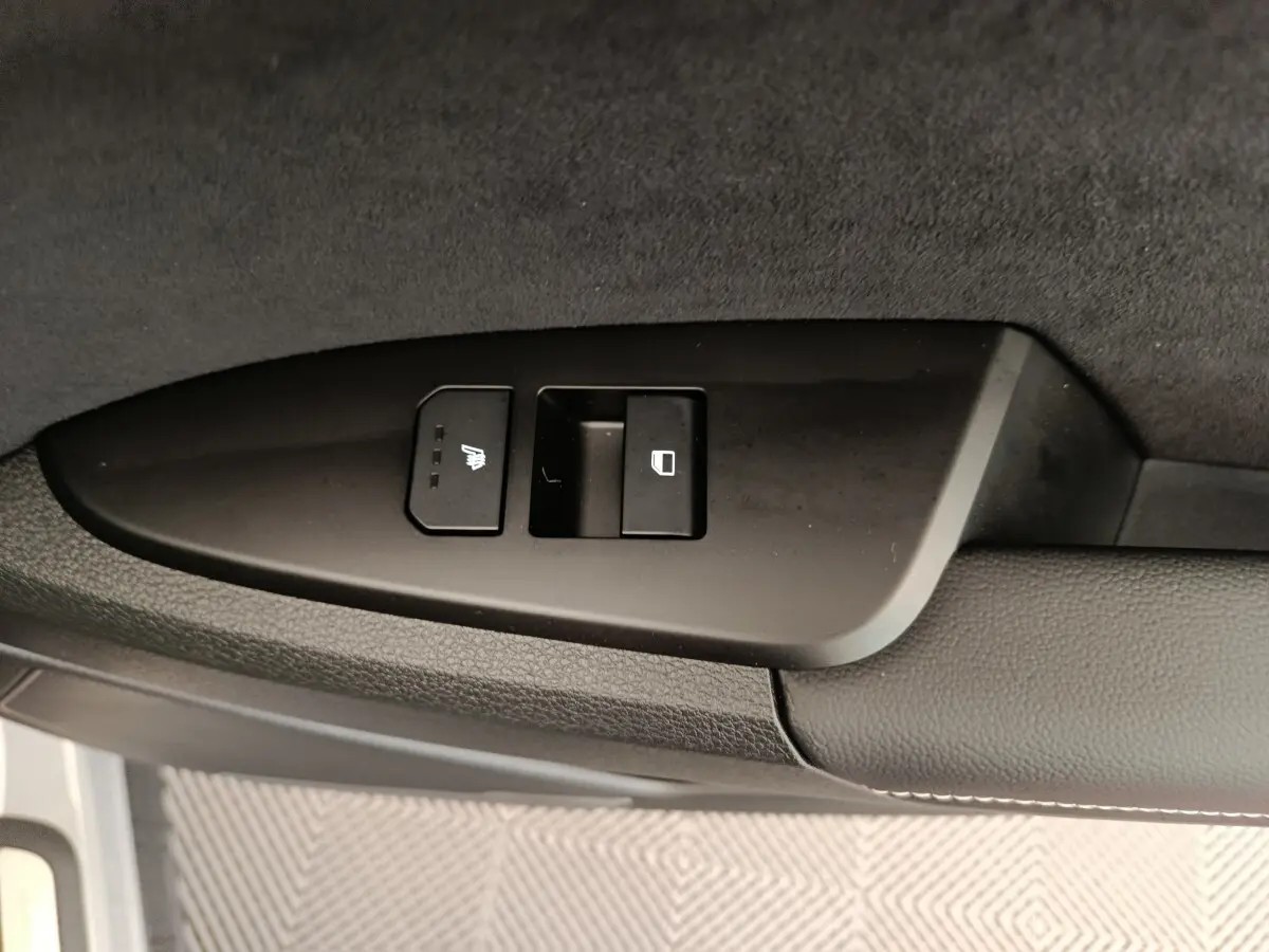 Gros plan sur les commandes de verrouillage et siège chauffant côté porte avant d’un Kia Sportage gris clair 2026.
