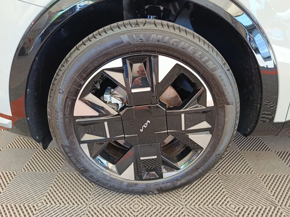 Gros plan sur la roue avant droite du KIA Sportage gris clair, avec jante noire au design géométrique distinctif.