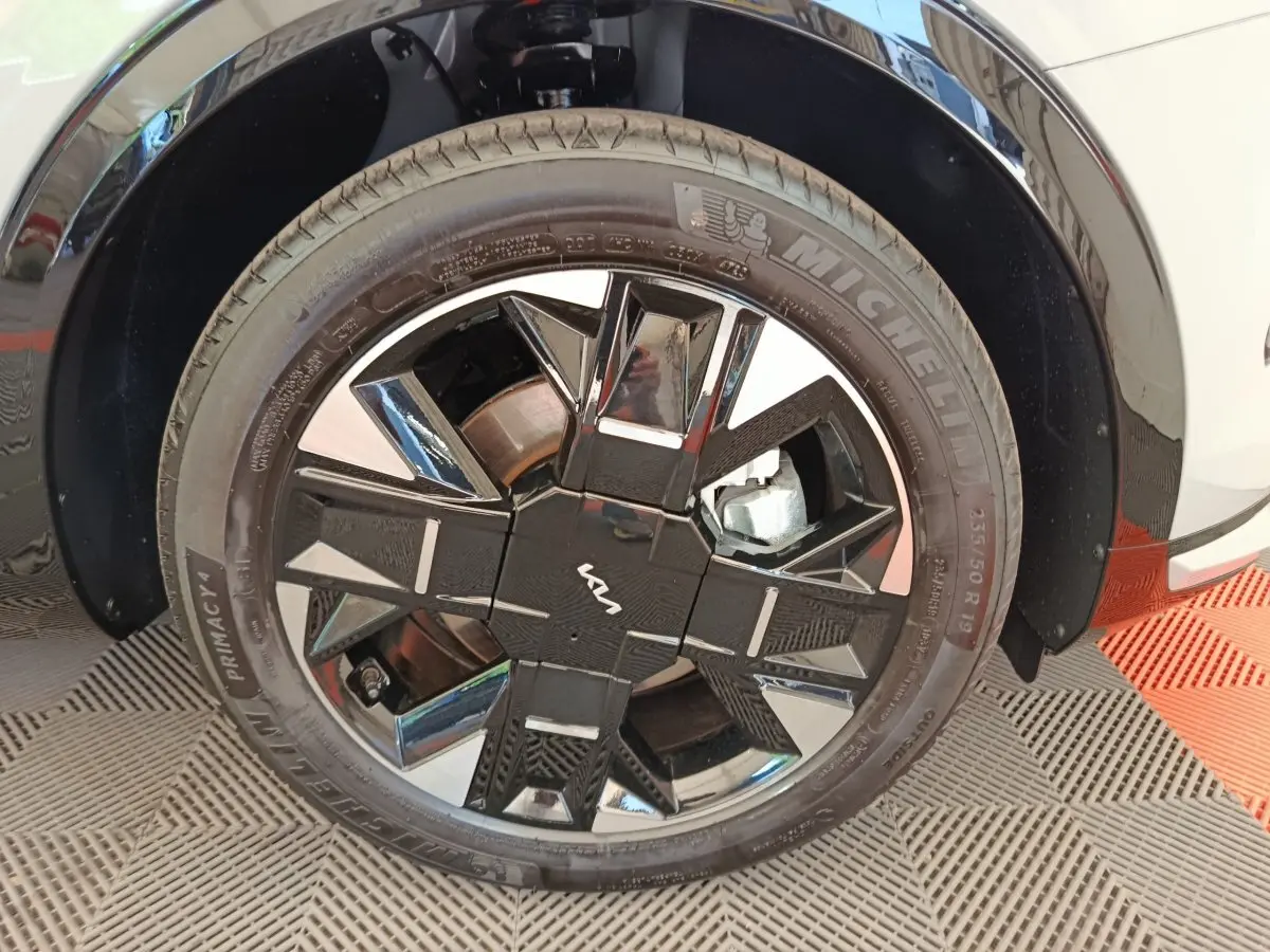 Gros plan sur la roue avant droite du Kia Sportage gris clair avec jante noire et argentée au design géométrique.