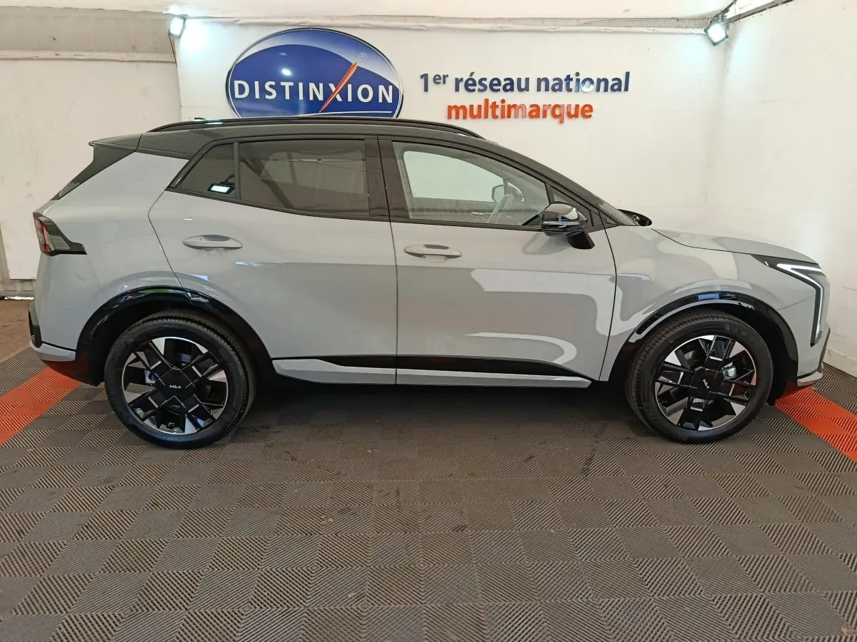 Vue de profil côté gauche du KIA SPORTAGE 1.6 T-GDI 239 HEV AUTO GT-LINE gris clair avec jantes noires et toit noir.