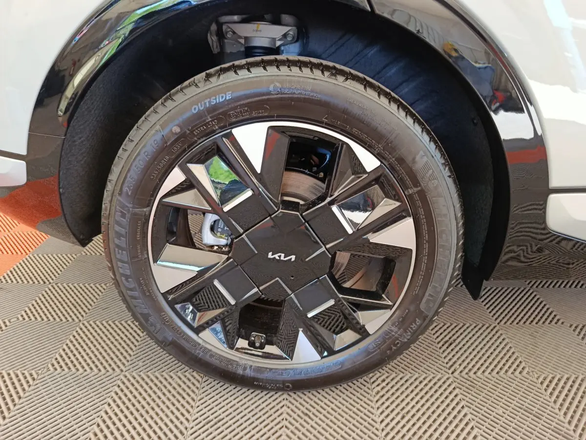 Gros plan sur la roue avant droite du KIA Sportage gris clair, mettant en valeur la jante noire et argentée au design géométrique.