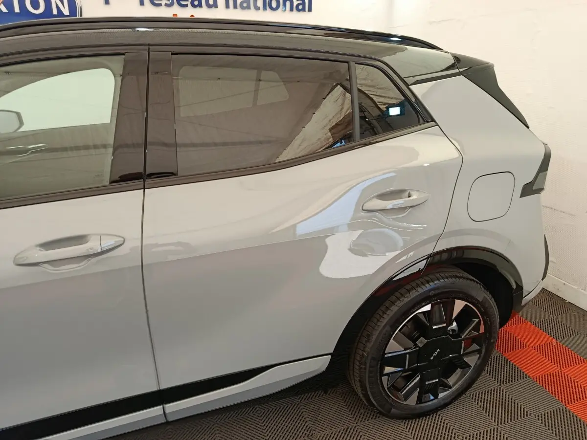 Vue côté droit arrière du Kia Sportage gris clair, mettant en valeur la porte arrière et la roue au design moderne noir brillant.