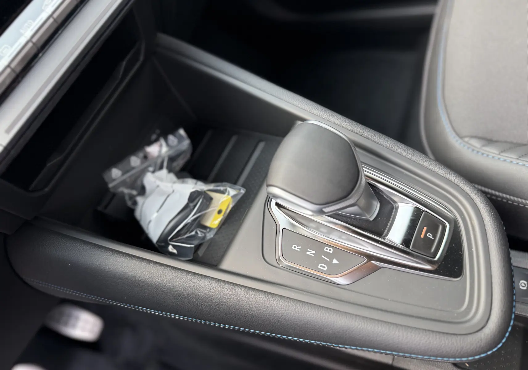Le levier de vitesses automatique noir du Renault Captur 2025, avec surpiqûres bleues sur la console centrale.