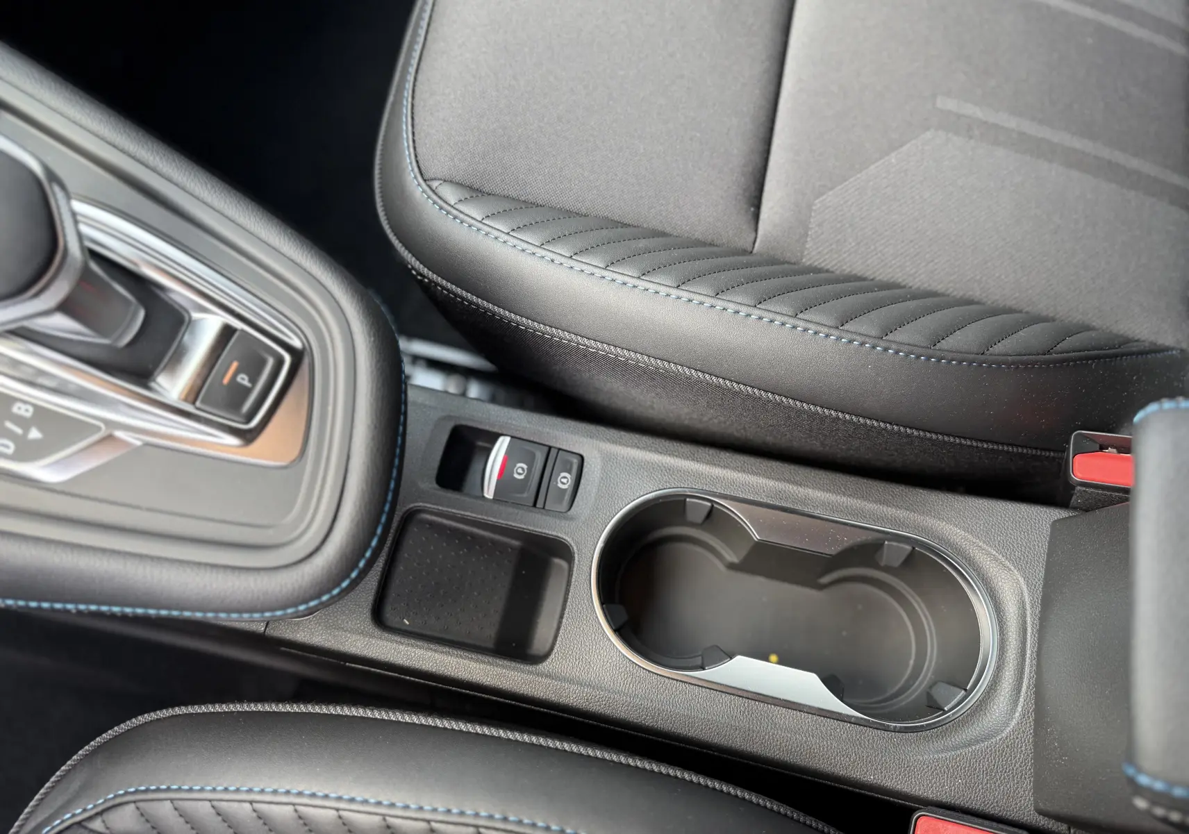 Gros plan sur la console centrale noire avec surpiqûres bleues et levier de vitesse automatique du Renault Captur 2025.
