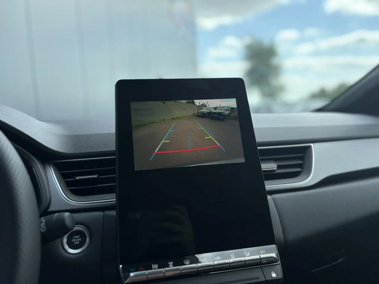 Vue intérieure du tableau de bord du Renault Captur gris Rafale, écran affichant la caméra de recul avec guidage coloré.