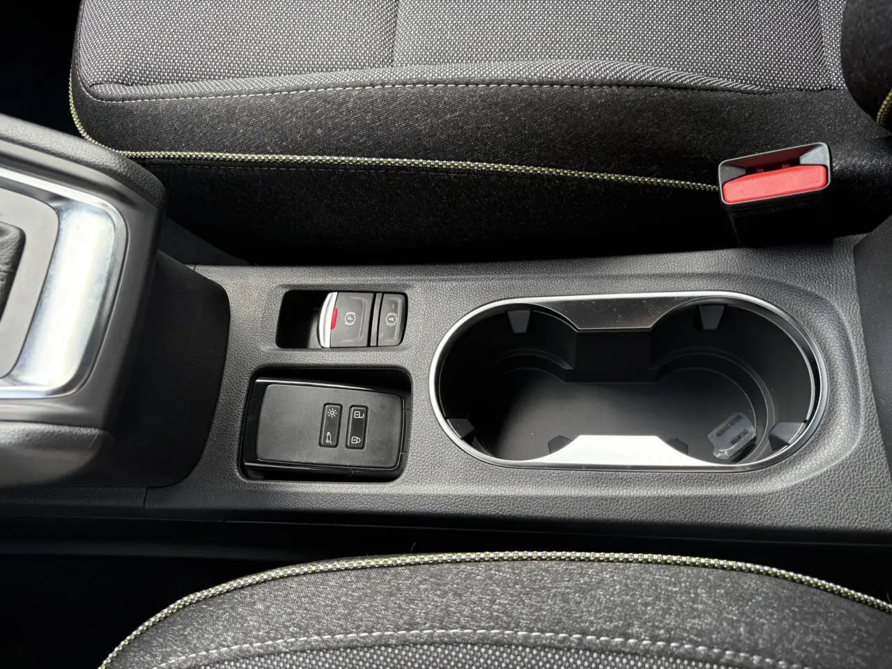 Gros plan sur la console centrale noire du Renault Captur gris Rafale, avec porte-gobelets et commandes électriques.
