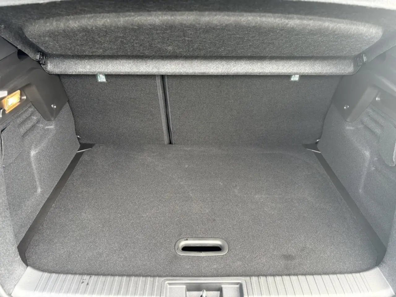Coffre ouvert du Renault Captur Gris Rafale, vue intérieure arrière montrant le volume de chargement et la moquette grise.