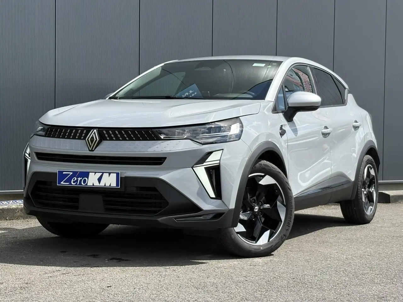 Renault Captur gris Rafale en 3/4 avant droit, avec jantes noires et calandre moderne au logo centré.