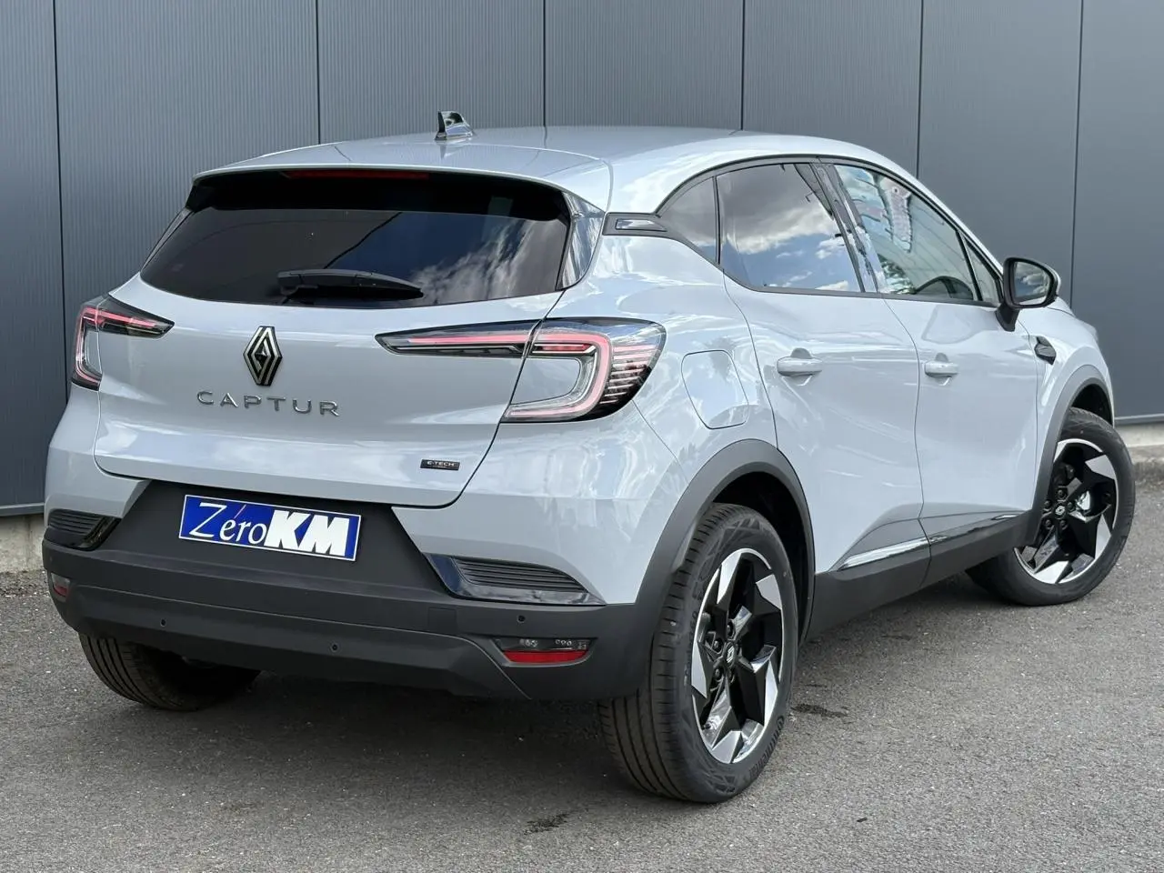 Vue 3/4 arrière droit d'un Renault Captur Gris Rafale avec jantes noires et vitres surteintées.