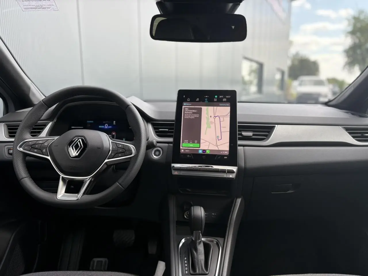 Intérieur du Renault Captur 2025 vu de face, tableau de bord noir avec écran tactile central et volant multifonction.