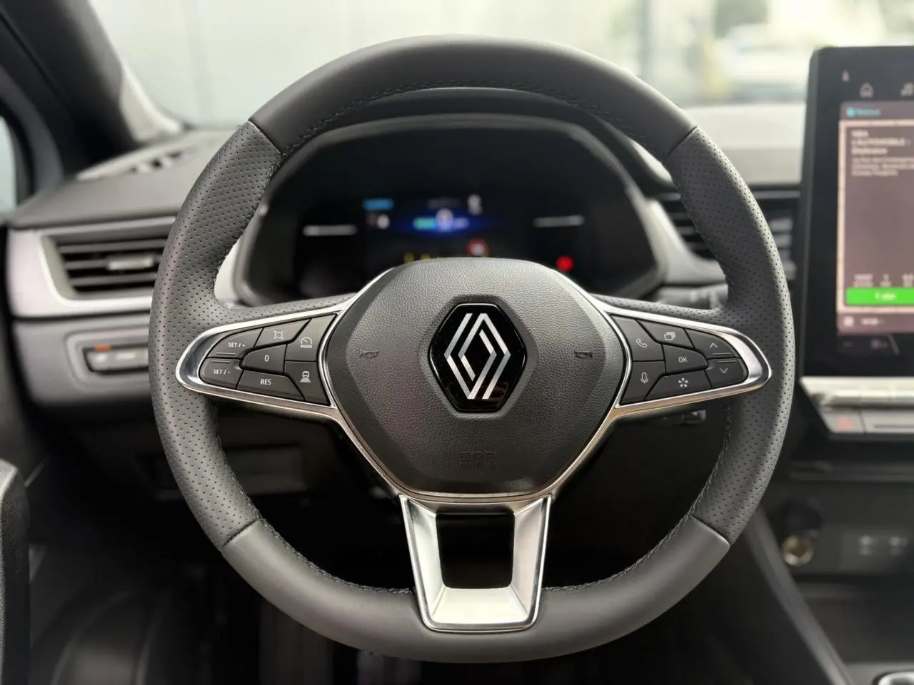 Volant en cuir perforé avec commandes intégrées du Renault Captur 2025, vue frontale centrée sur le logo Renault.