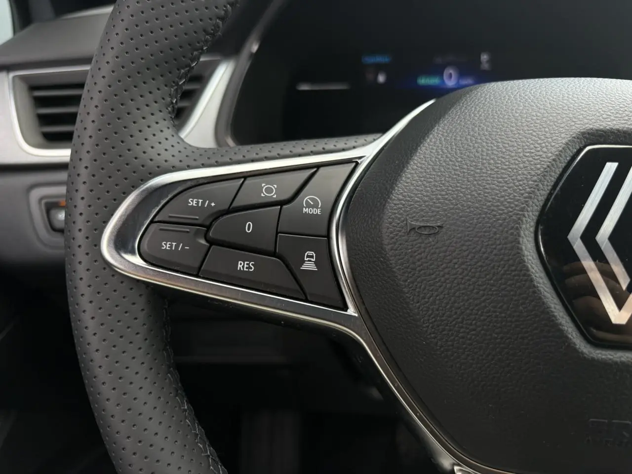 Gros plan sur les commandes du volant à gauche du Renault Captur gris Rafale, mettant en valeur les boutons du régulateur adaptatif.