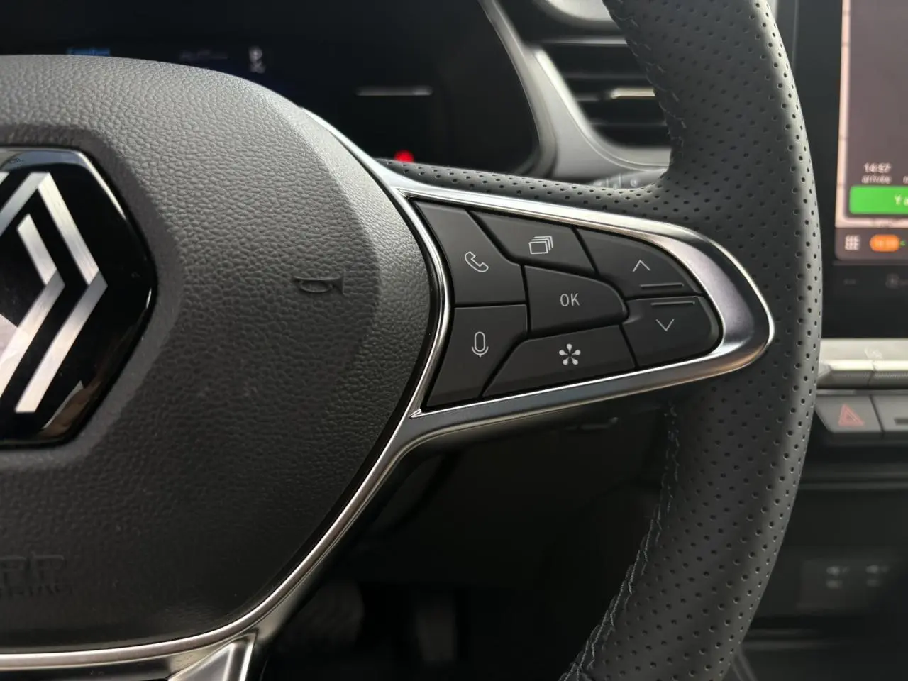 Gros plan sur le volant perforé côté droit du Renault Captur gris Rafale avec commandes multifonctions et tableau de bord numérique.