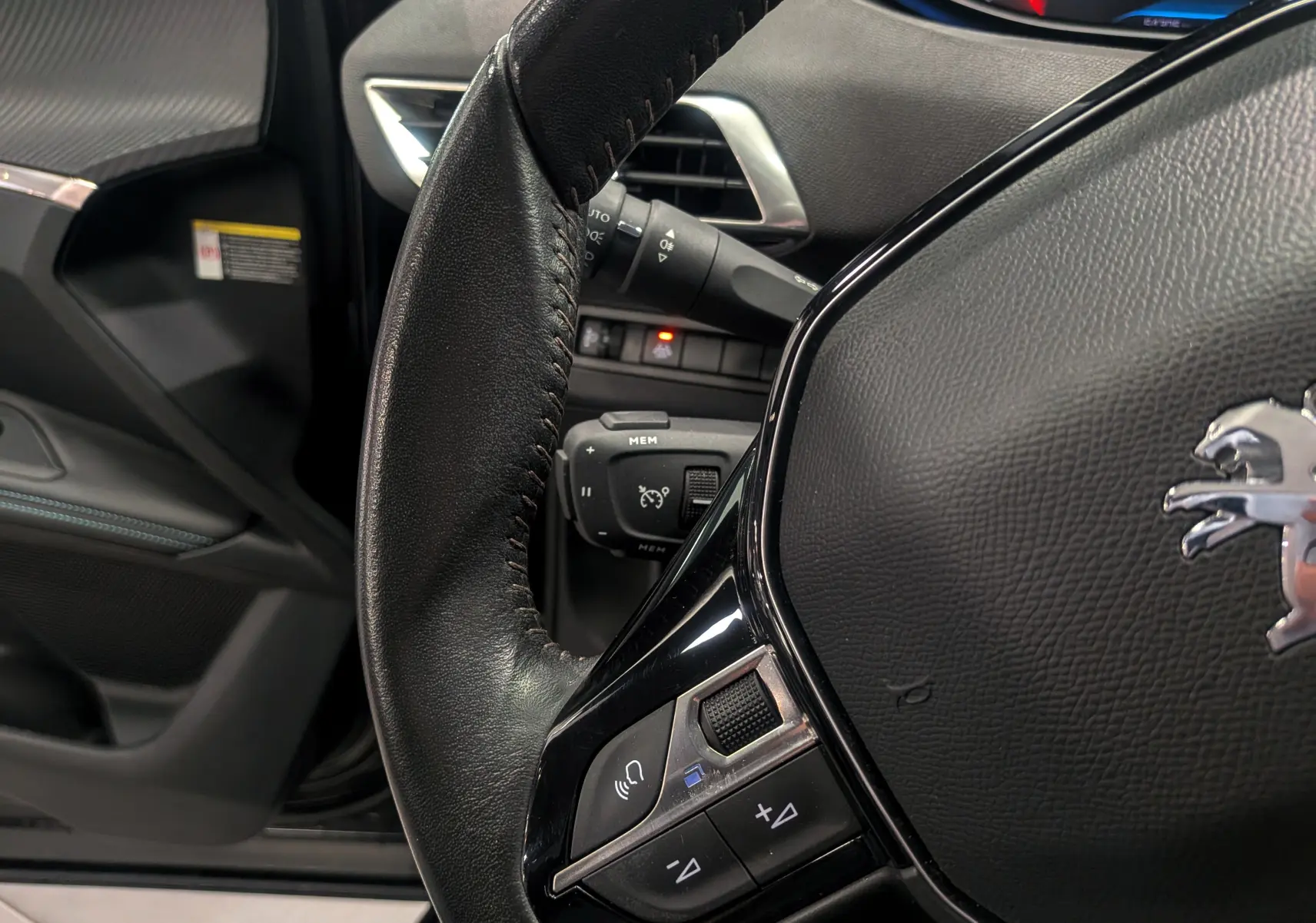 Gros plan sur le volant en cuir noir du Peugeot 3008 BlueHDi 130 Allure 2022 avec commandes intégrées, intérieur noir Perla.