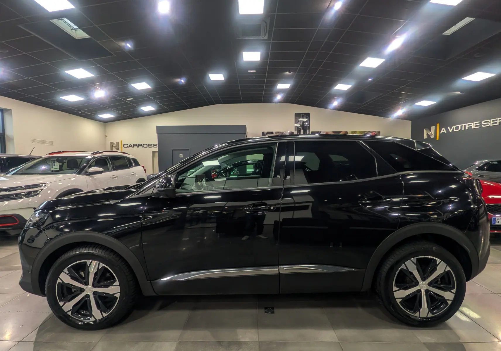 Peugeot 3008 BlueHDi 130 en noir Perla vue de profil côté gauche, avec jantes alliage bicolores en showroom.