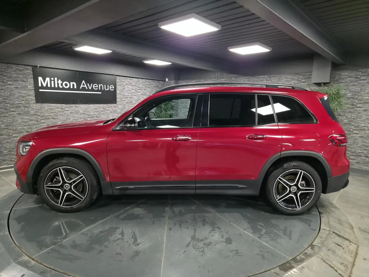 Vue latérale droite d'un Mercedes GLB rouge Patagonie avec jantes AMG 19 pouces et vitres teintées foncées.