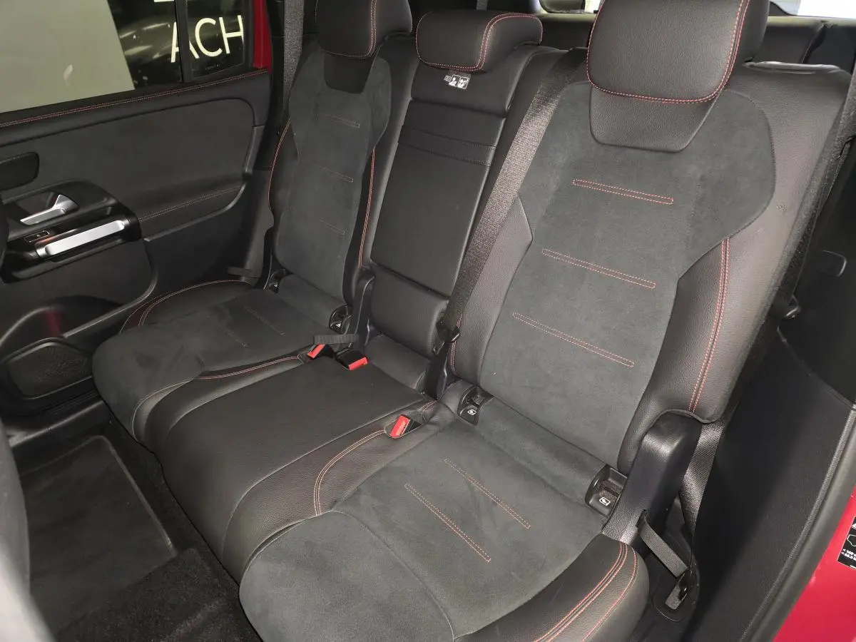 Vue intérieure côté gauche des sièges arrière en similicuir noir avec surpiqûres rouges du Mercedes GLB 200 d AMG Line rouge Patagonie