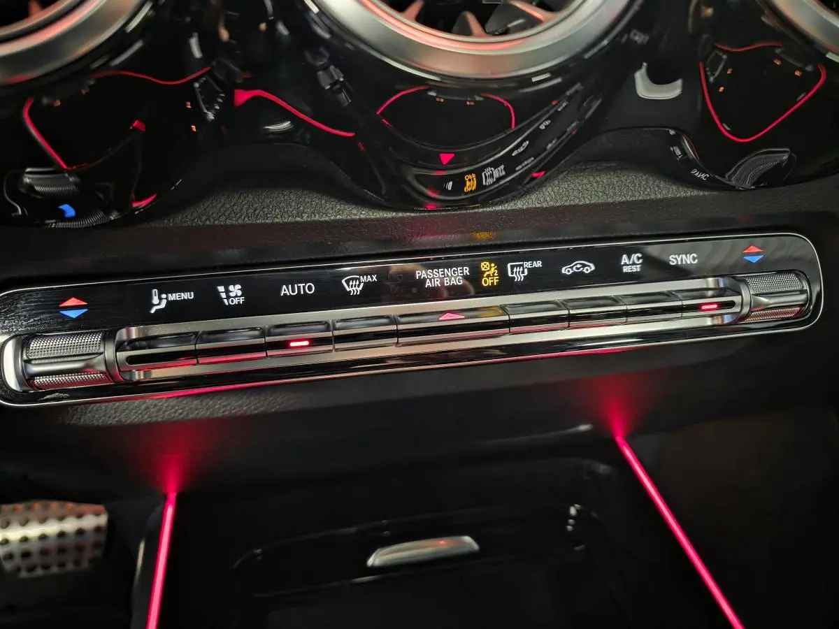 Détail de la console centrale du Mercedes GLB 200 d AMG Line 2022 avec éclairage d'ambiance rouge et commandes climatisation digitales.