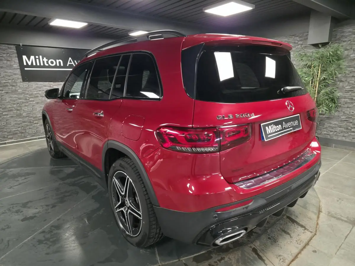 Vue 3/4 arrière droite d'un Mercedes GLB 200 d AMG Line rouge Patagonie avec jantes AMG noires et baguettes chromées.