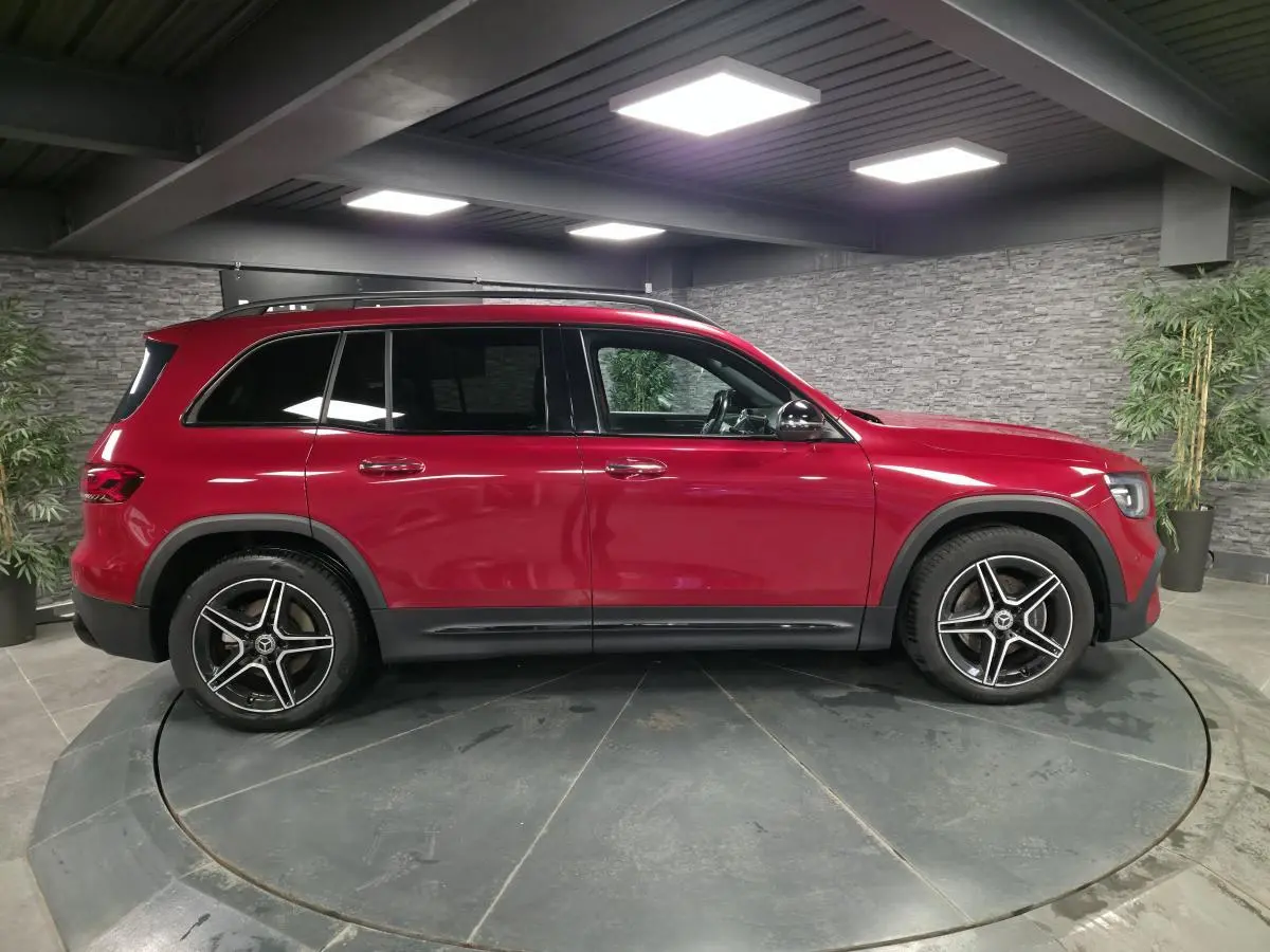 Vue de profil côté gauche d'un Mercedes GLB 200 d AMG Line rouge avec jantes AMG 19 pouces noir et argent.