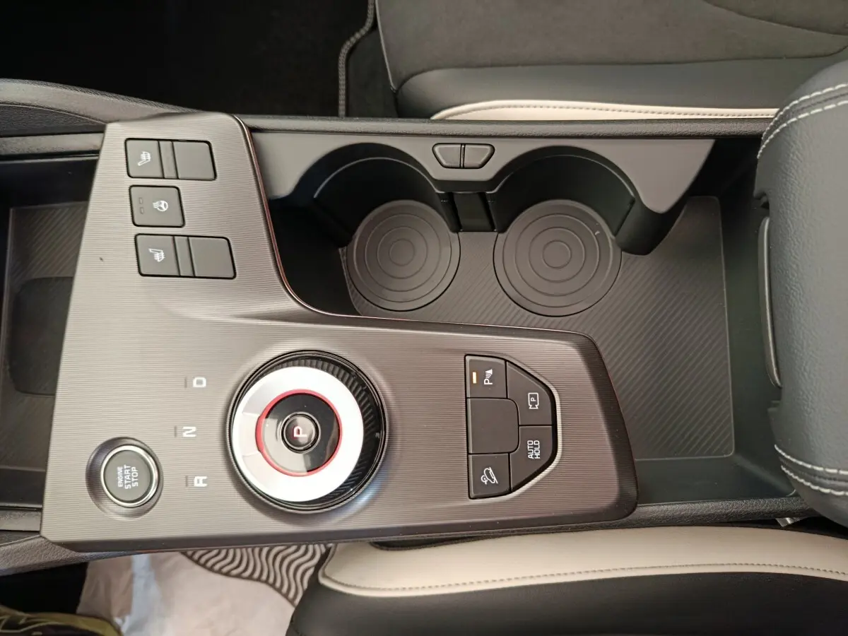 Vue en plongée du sélecteur de boîte automatique et des commandes sur la console centrale du Kia Sportage gris foncé.