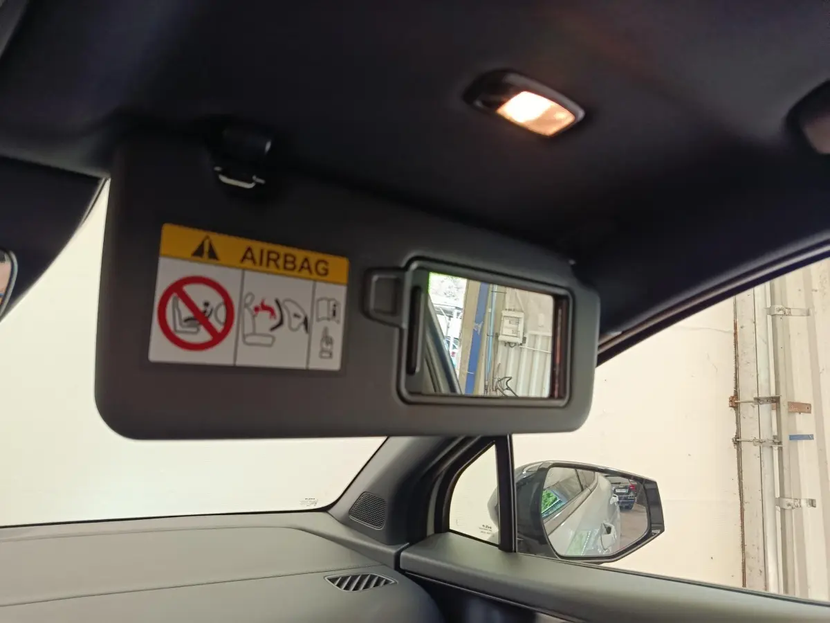 Vue intérieure du pare-soleil côté conducteur avec miroir et rétroviseur, dans un Kia Sportage gris foncé.