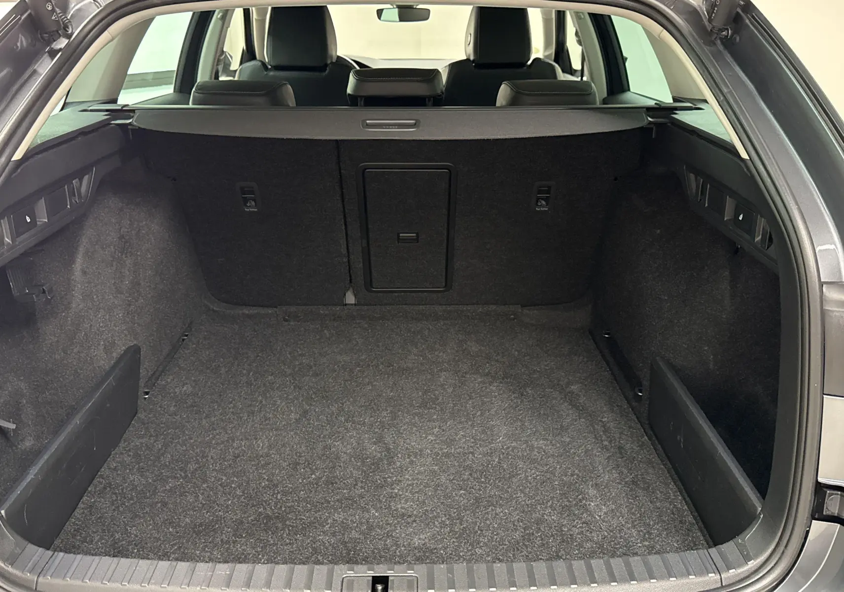 Coffre ouvert d'une Skoda Octavia Combi gris graphite 2023, vue arrière montrant un grand espace de chargement vide.