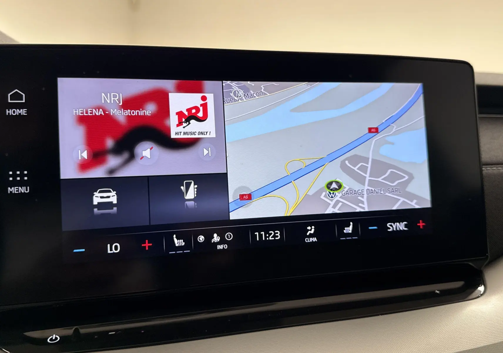 Écran tactile central du Skoda Octavia Combi gris graphite 2023, affichant navigation et radio NRJ en intérieur.