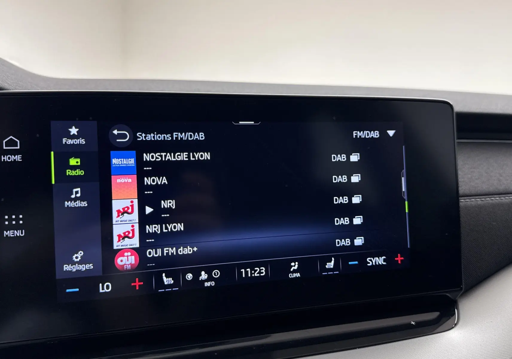Écran tactile central de la Skoda Octavia Combi gris graphite 2023 affichant les stations radio FM/DAB en mode menu.