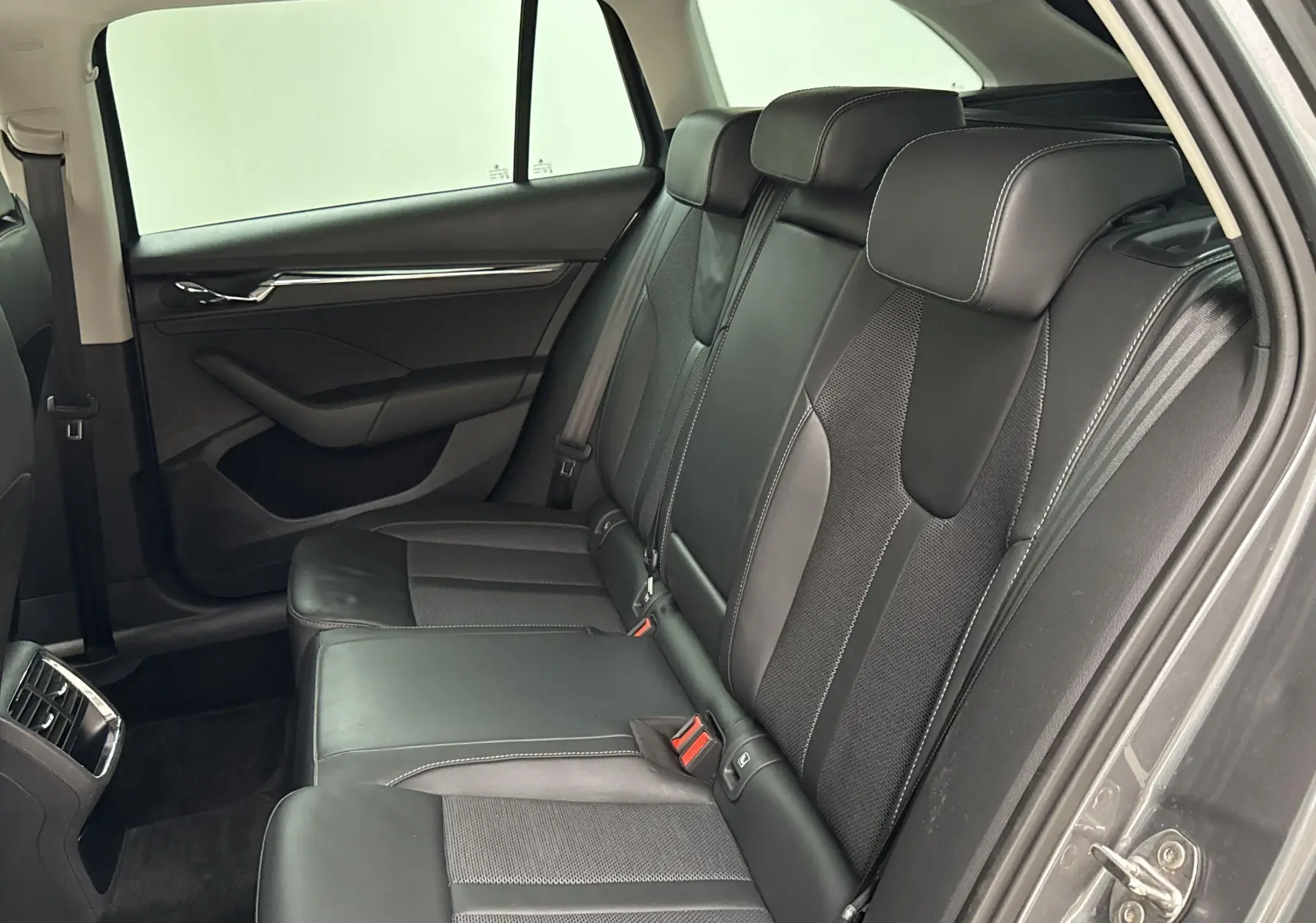Vue intérieure côté droit des sièges arrière en cuir noir du Skoda Octavia Combi gris graphite 2023.