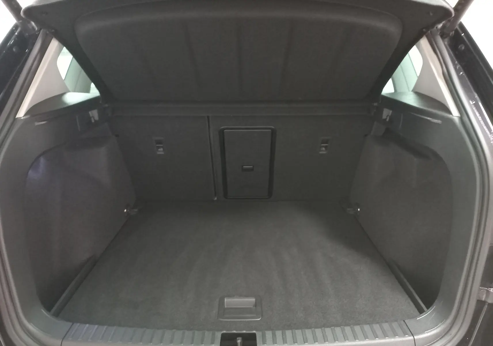 Coffre ouvert du SEAT Ateca Noir Magic Nacré 2025, vue arrière montrant l'espace de chargement vide et la trappe centrale.