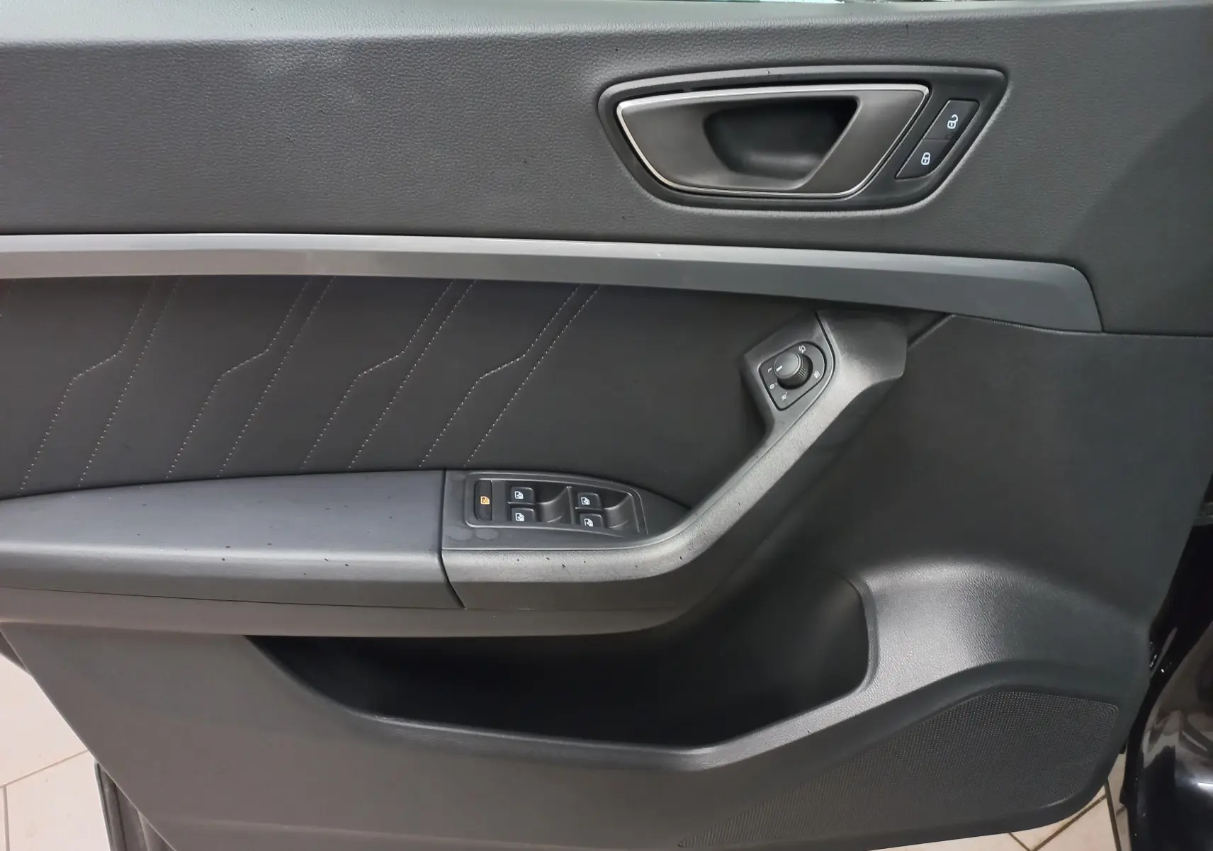 Gros plan sur la porte intérieure côté conducteur du SEAT Ateca noir avec commandes de vitres et verrouillage.