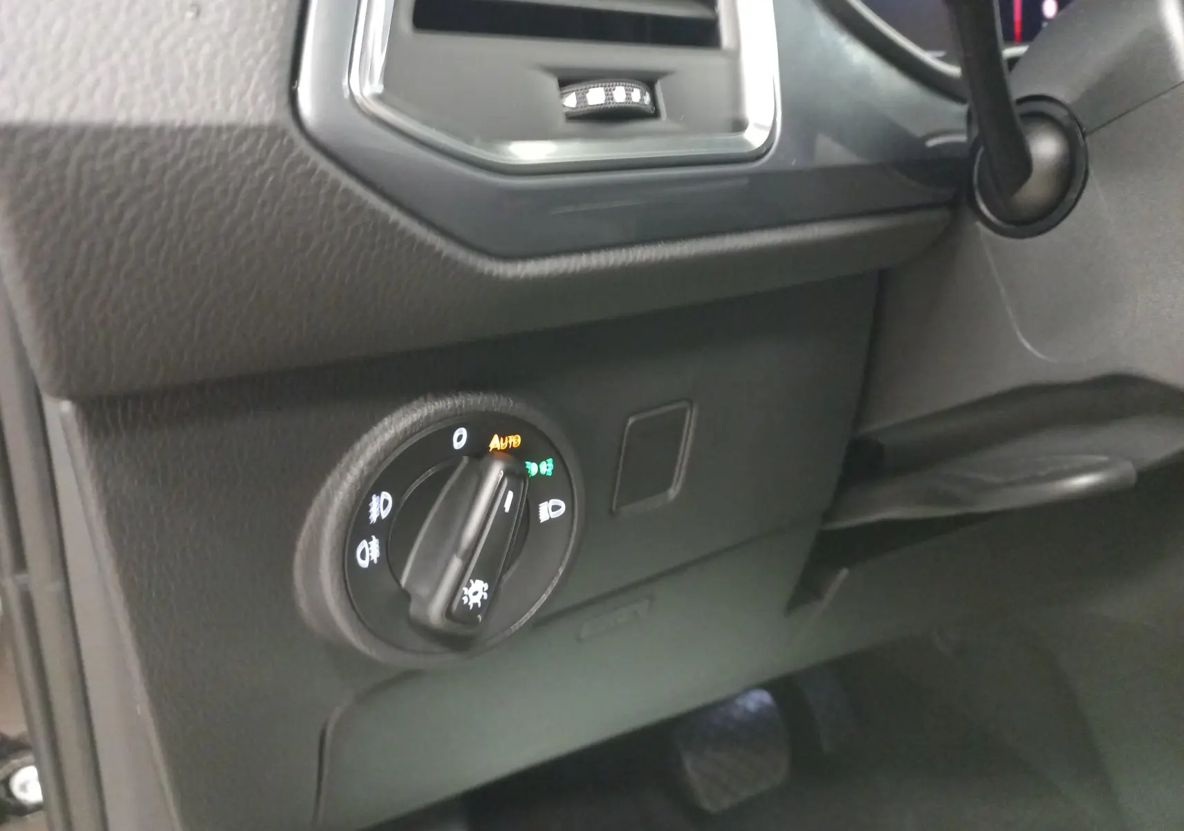 Gros plan sur le bouton de commande des phares dans l'habitacle noir du SEAT Ateca 2025 côté gauche.