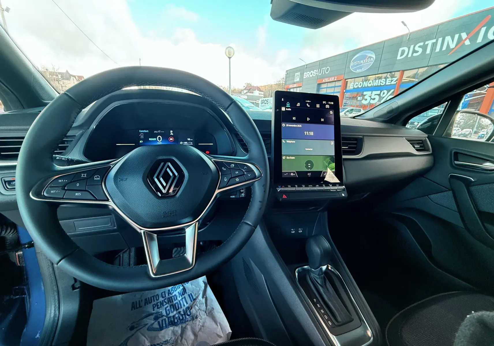 Vue intérieure avant du Renault Captur E-Tech Hybrid 2025, tableau de bord avec écran tactile vertical et volant multifonction noir.