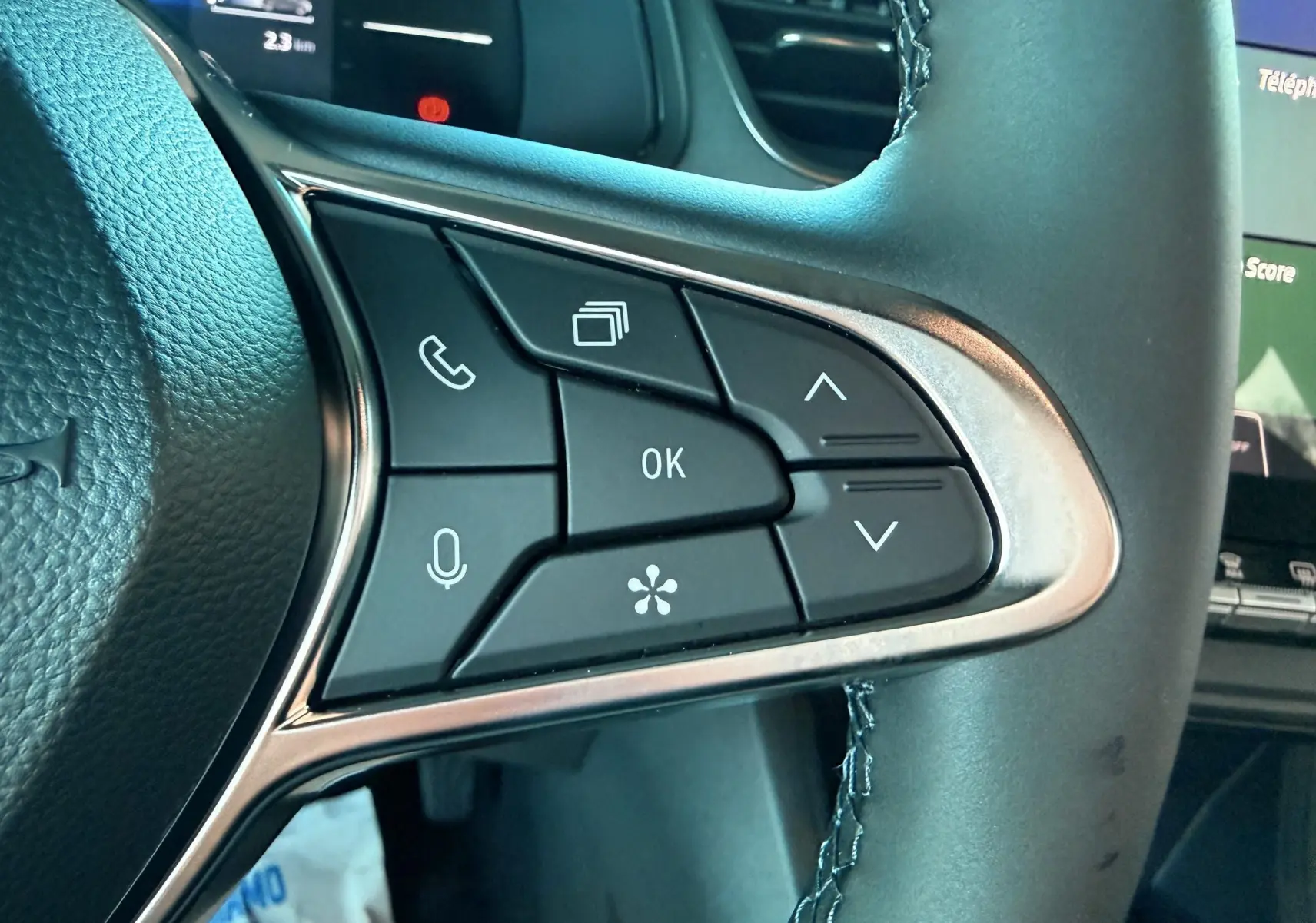 Gros plan sur les commandes au volant à gauche du Renault Captur 2025 hybride bleu iron metal avec toit noir.