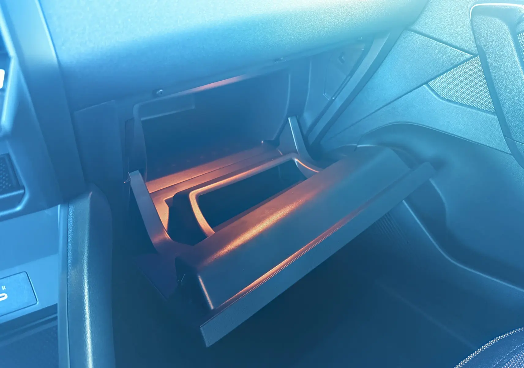 Gros plan sur la boîte à gants ouverte côté passager du Renault Captur hybride 2025, intérieur noir.